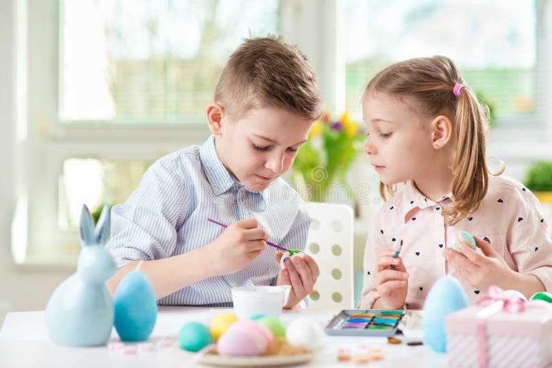 Två lyckliga barn som har gyckel under målningägg för easter in royaltyfri bild Två lyckliga barn som har gyckel under målningägg för easter in royaltyfri bild