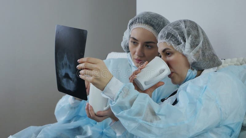 Två läkare undersöker en patientes röntgendiagnostik under en tepaus stock video