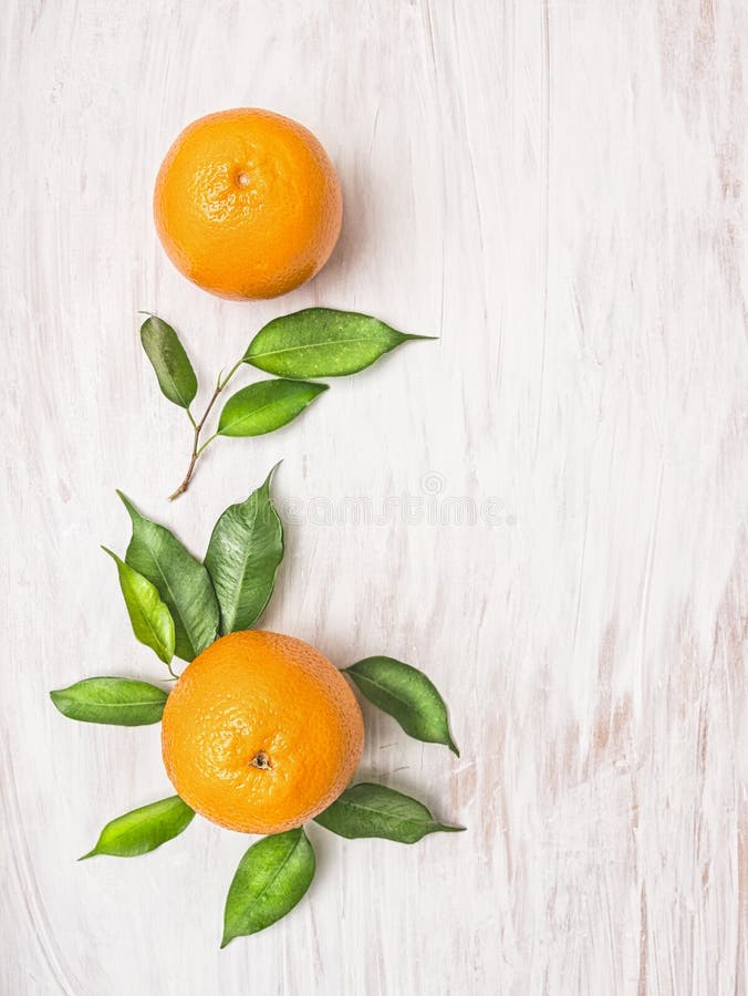 Två orange frukter med gröna sidor på med träbakgrund royaltyfri foto