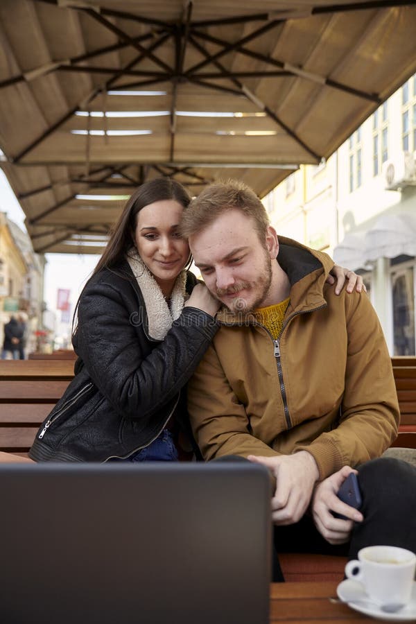 Två personer som kramar par som ser en bärbar datordator i ett kafé royaltyfria bilder Två personer som kramar par som ser en bärbar datordator i ett kafé royaltyfria bilder