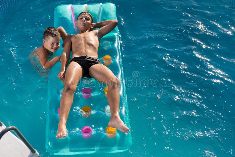Två pojkar simmar i poolen på en luftmadrass som är ett lyckligt sommarkoncept för barn arkivfoto Två pojkar simmar i poolen på en luftmadrass som är ett lyckligt sommarkoncept för barn arkivfoto