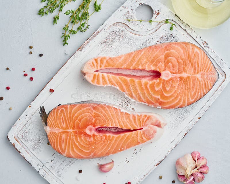 Två rå laxbiffar, fisk filea, stora skivade delar på skärbräda på en vit tabell Top besk?dar m?nga bakgrundsklimpmat meat mycket fotografering för bildbyråer Två rå laxbiffar, fisk filea, stora skivade delar på skärbräda på en vit tabell Top besk?dar m?nga bakgrundsklimpmat meat mycket fotografering för bildbyråer