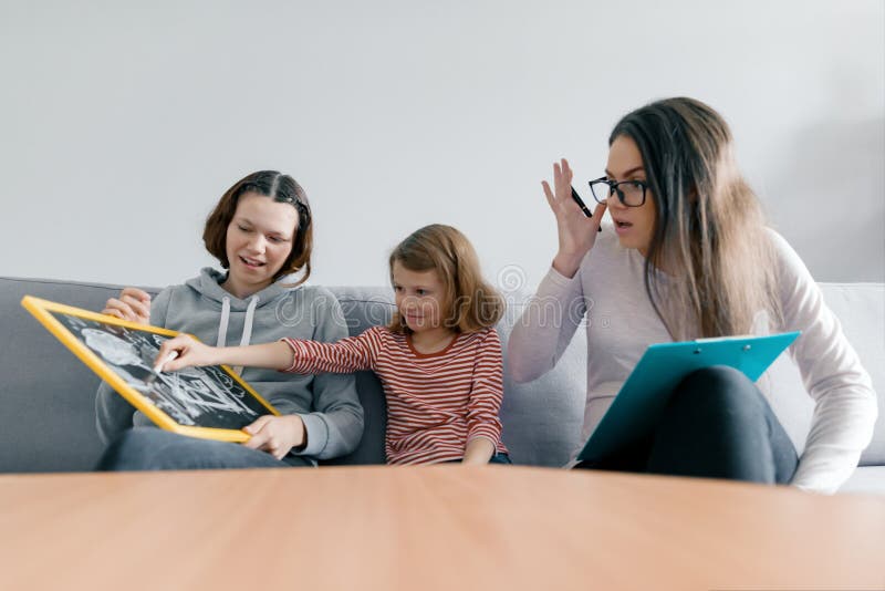 Två systerflickor som talar med familjpsykologen för ung kvinna, barn som i regeringsställning sitter royaltyfria bilder Två systerflickor som talar med familjpsykologen för ung kvinna, barn som i regeringsställning sitter royaltyfria bilder