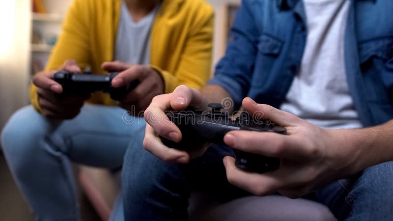 Två tonårspojkar med flera etniska tonåringar som spelar datorspel hemma, med nära hand arkivfoto