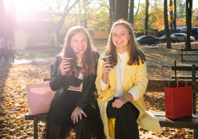 Två unga flickor som håller kaffekoppar på väg arkivbilder