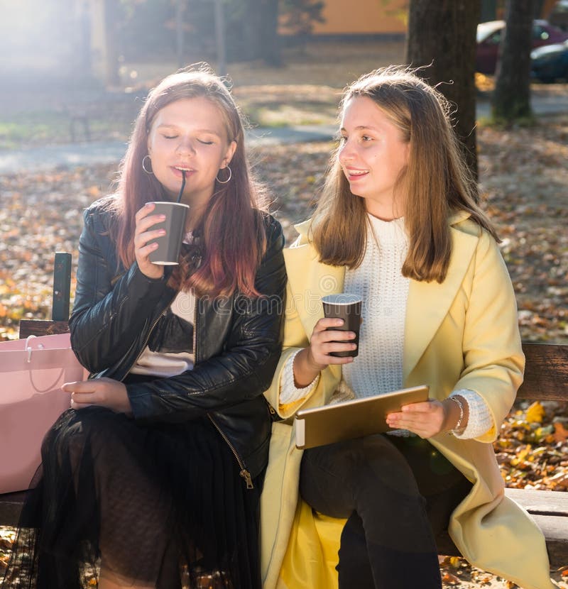 Två unga flickor som håller kaffekoppar på väg arkivbild