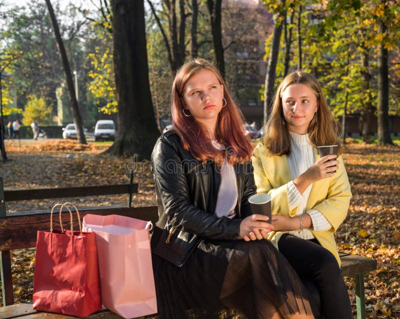 Två unga flickor som håller kaffekoppar på väg royaltyfri foto