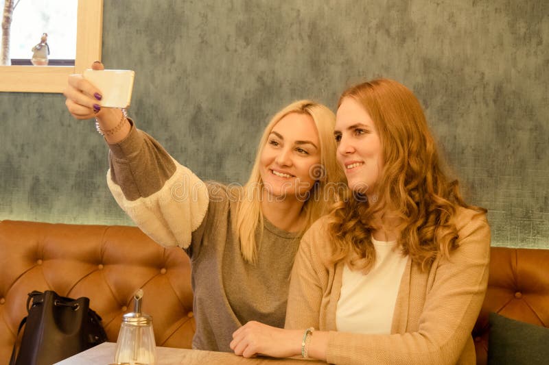 Två unga härliga flickor som använder den smarta telefonen och in gör selfie royaltyfri foto Två unga härliga flickor som använder den smarta telefonen och in gör selfie royaltyfri foto