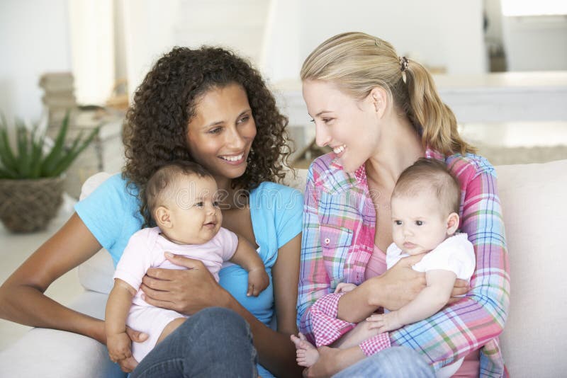 Two Young Mothers On Sofa At Home. Two Young Mothers On Sofa At Home