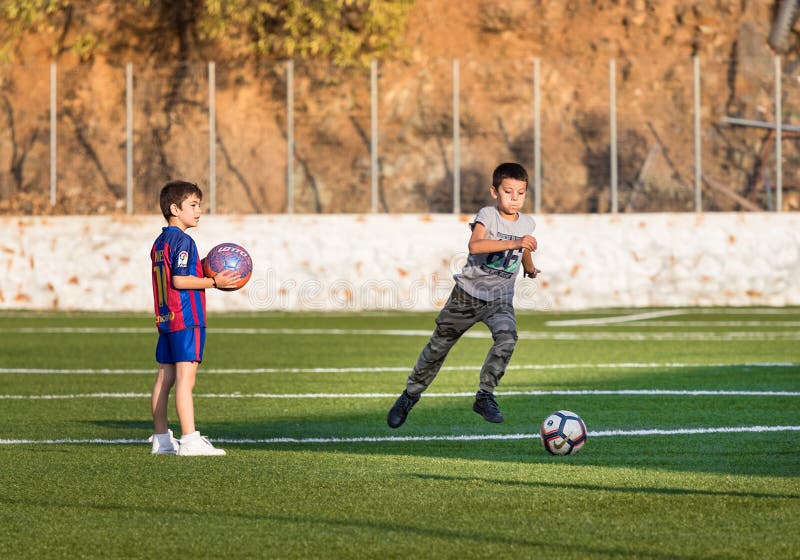 Två ungar som spelar fotboll i ett fotbollfält ett av dem med hydraen för Barcelona skjortaiin, Grekland arkivbild Två ungar som spelar fotboll i ett fotbollfält ett av dem med hydraen för Barcelona skjortaiin, Grekland arkivbild
