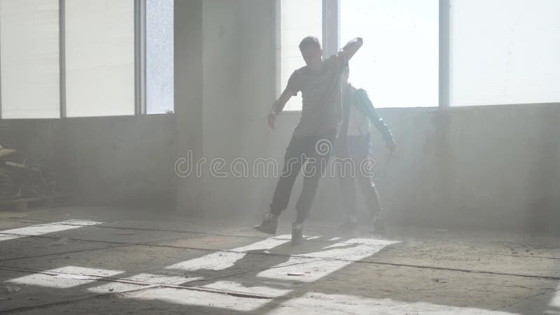 Två vänner av lyckade dansare dansar breakdance i en övergiven dammig byggnad Utbildande kompetenta höfthopers