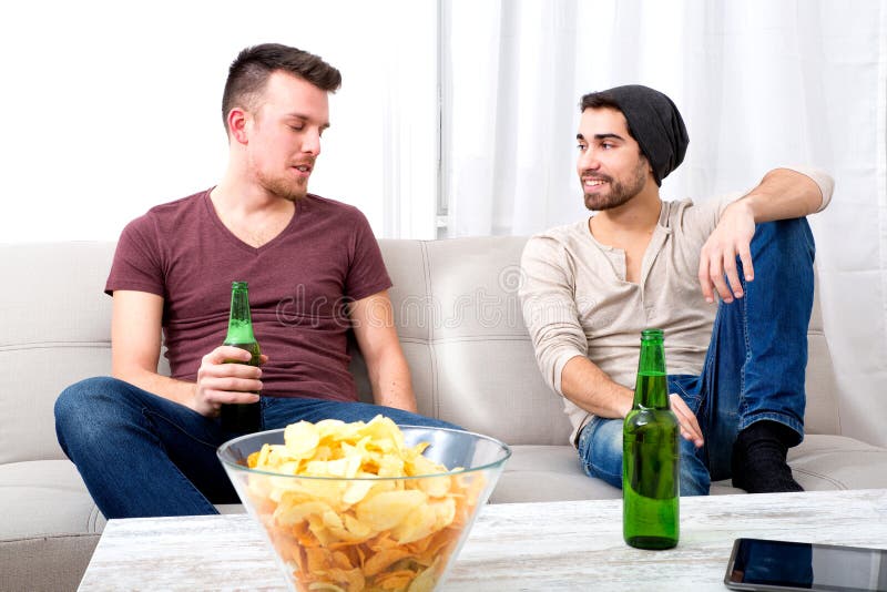 Två vänner som har en konversation i vardagsrummet arkivfoto Två vänner som har en konversation i vardagsrummet arkivfoto