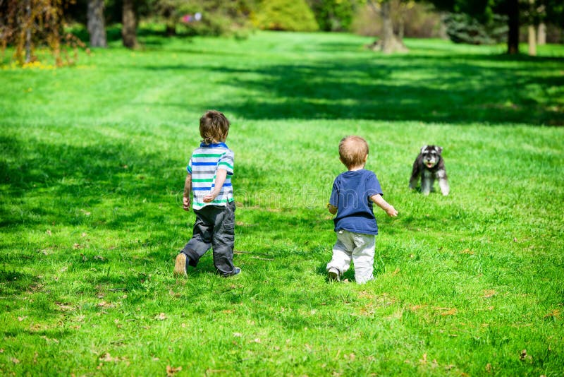 Två Young Boys på en parkera som att närma sig en hund royaltyfri fotografi Två Young Boys på en parkera som att närma sig en hund royaltyfri fotografi