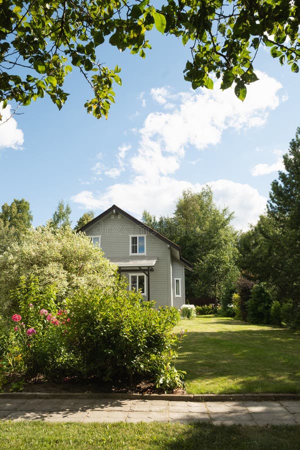 Tvåvåvåningshus på landsbygden under sommaren med buskgräta träd och blommande träd. Ryska royaltyfri foto
