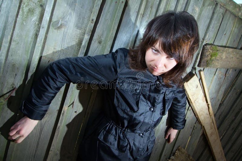 Tough young girl in black clothes and old wooden fence. Tough young girl in black clothes and old wooden fence.