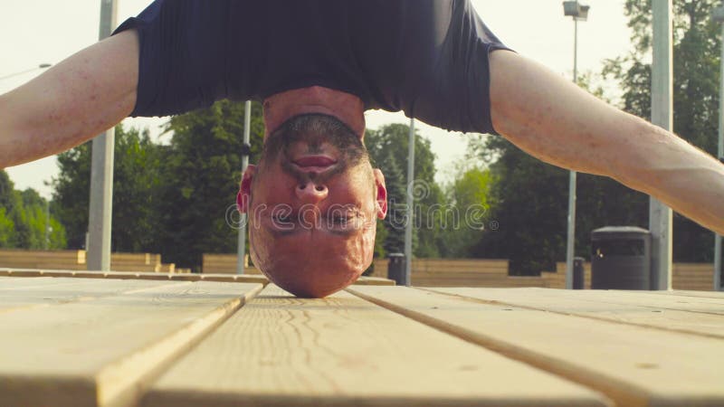 Twarz mężczyzna robi headstand w parku