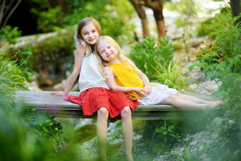 Twee aanbiddelijke kleine zusters die en op warme en zonnige de zomerdag lachen koesteren stock fotografie Twee aanbiddelijke kleine zusters die en op warme en zonnige de zomerdag lachen koesteren stock fotografie