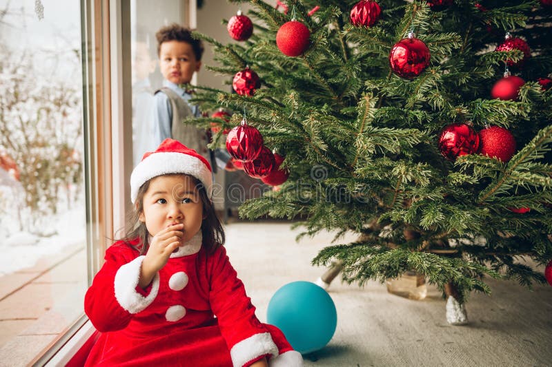Twee aanbiddelijke 3 éénjarigenjonge geitjes die door de Kerstboom spelen royalty-vrije stock afbeelding Twee aanbiddelijke 3 éénjarigenjonge geitjes die door de Kerstboom spelen royalty-vrije stock afbeelding