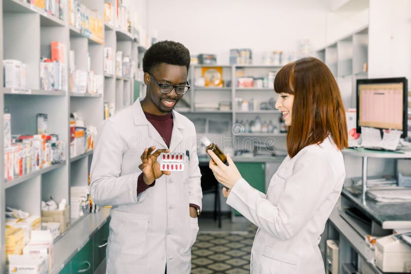 Twee apothekersman en vrouw die in drogisterij werken Mannelijke en vrouwelijke apothekers die geneesmiddelen kwaliteit controler stock fotografie Twee apothekersman en vrouw die in drogisterij werken Mannelijke en vrouwelijke apothekers die geneesmiddelen kwaliteit controler stock fotografie