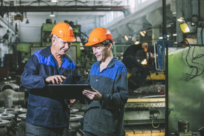 Twee arbeiders bij een bedrijf met een in hand tablet, workin stock afbeeldingen Twee arbeiders bij een bedrijf met een in hand tablet, workin stock afbeeldingen