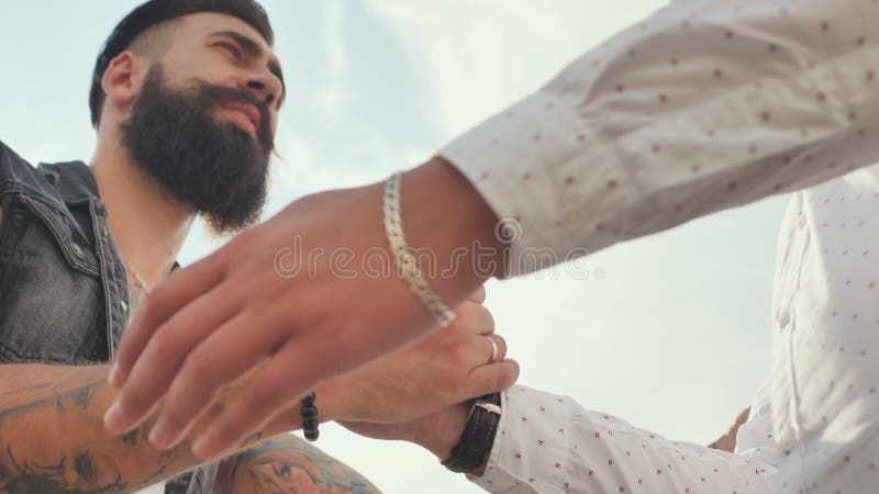 Twee brutale mensen met een baard begroeten elkaar met een handdruk