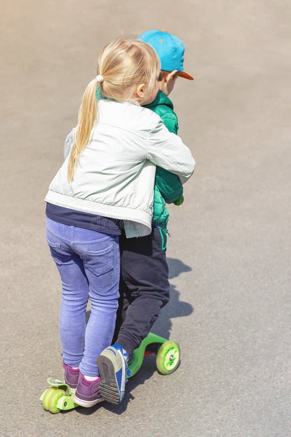 Twee frinedsjongen en meisje die pret hebben die één autoped samen gelijktijdig berijden Kinderensiblings, broer en zuster royalty-vrije stock foto's Twee frinedsjongen en meisje die pret hebben die één autoped samen gelijktijdig berijden Kinderensiblings, broer en zuster royalty-vrije stock foto's