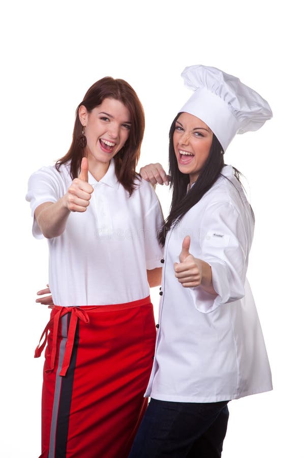 A studio view of two female cooks giving a happy thumbs up. White background. A studio view of two female cooks giving a happy thumbs up. White background.