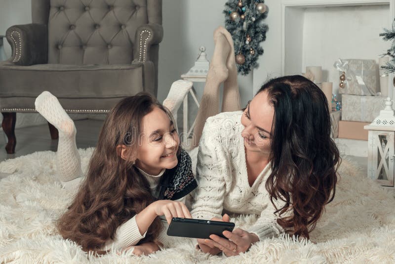 Twee gelukkige meisjes, de moeder en de dochter liggen op een vloer in Nieuwjaar royalty-vrije stock fotografie Twee gelukkige meisjes, de moeder en de dochter liggen op een vloer in Nieuwjaar royalty-vrije stock fotografie