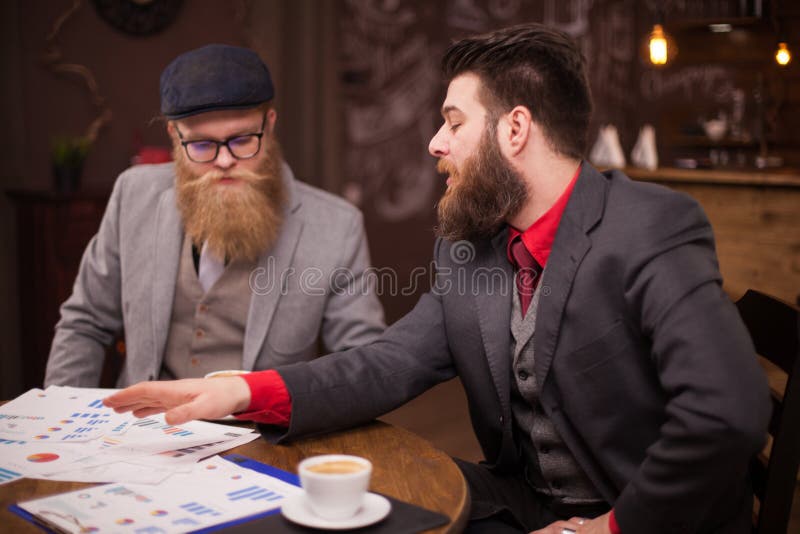 Twee gelukkige stafmedewerkers die in een koffiewinkel samenkomen en een bedrijfsgesprek hebben royalty-vrije stock afbeeldingen Twee gelukkige stafmedewerkers die in een koffiewinkel samenkomen en een bedrijfsgesprek hebben royalty-vrije stock afbeeldingen