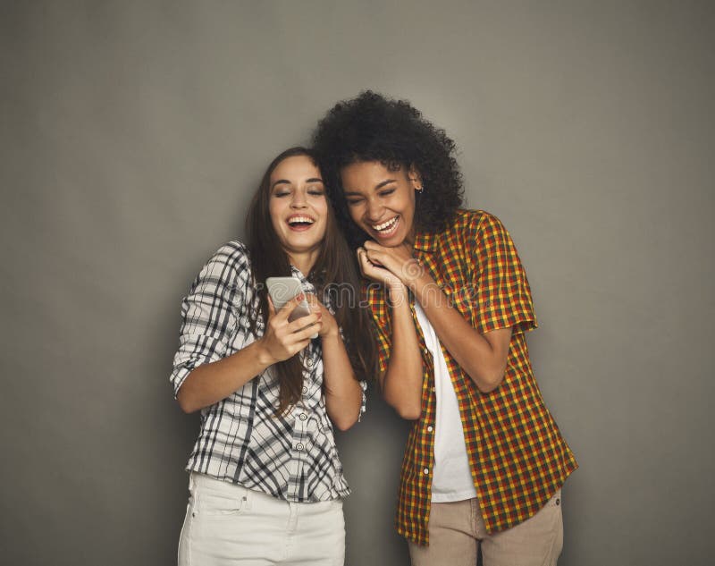 Twee gelukkige vrouwelijke vrienden die smartphone gebruiken royalty-vrije stock foto Twee gelukkige vrouwelijke vrienden die smartphone gebruiken royalty-vrije stock foto