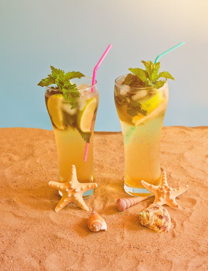 Twee glazen van mojitococktail met het drinken stro op zandstrand op blauwe achtergrond royalty-vrije stock foto Twee glazen van mojitococktail met het drinken stro op zandstrand op blauwe achtergrond royalty-vrije stock foto