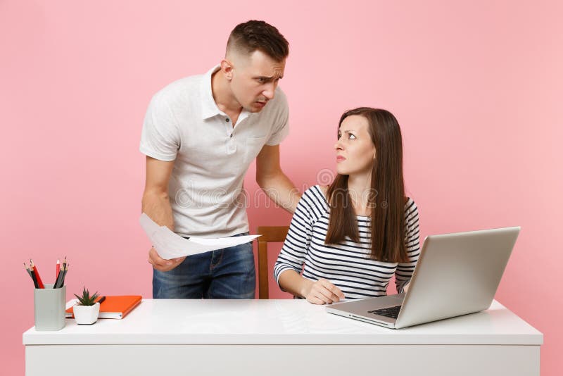 Twee glimlachende bedrijfsvrouwenman collega's zitten het werk bij wit bureau met eigentijdse laptop op pastelkleur roze achtergr stock afbeelding Twee glimlachende bedrijfsvrouwenman collega's zitten het werk bij wit bureau met eigentijdse laptop op pastelkleur roze achtergr stock afbeelding