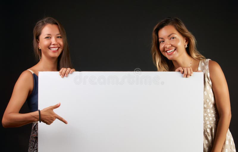 Twee glimlachende vrouwen die een lege banner houden stock afbeeldingen Twee glimlachende vrouwen die een lege banner houden stock afbeeldingen