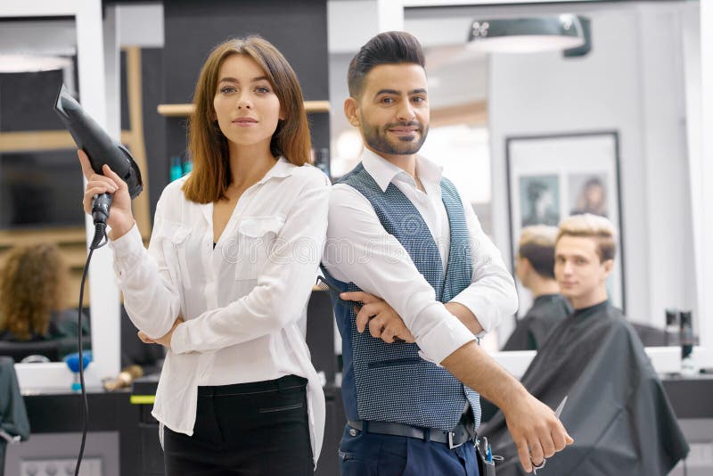 Twee hairstylers stellen die zich in moderne spacy beaty salon bevinden stock foto Twee hairstylers stellen die zich in moderne spacy beaty salon bevinden stock foto