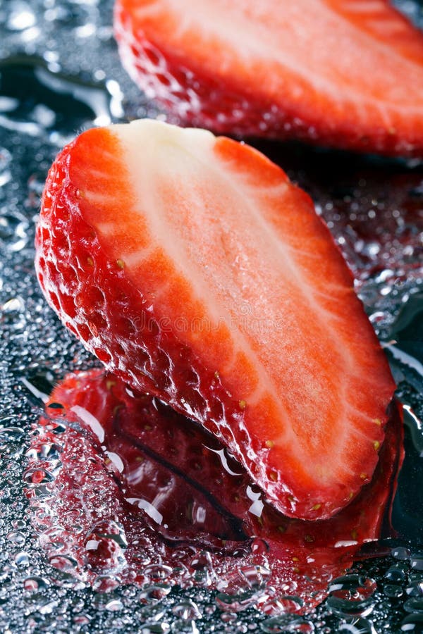 Twee halve verse aardbeien met watermacro stock fotografie Twee halve verse aardbeien met watermacro stock fotografie