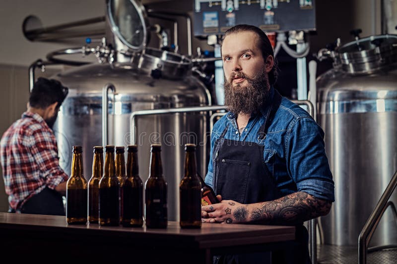 Twee hipster tussen verschillende rassen volledige gebaarde mannetjes in overhemden en schorten die in de brouwerij werken royalty-vrije stock foto Twee hipster tussen verschillende rassen volledige gebaarde mannetjes in overhemden en schorten die in de brouwerij werken royalty-vrije stock foto