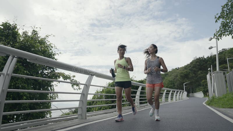 Twee jonge aziatische vrouwen die in de openlucht joggen