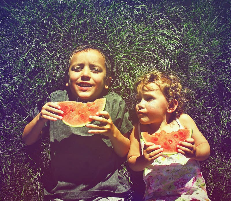 Twee jonge geitjes die die watermeloen eten met een retro uitstekende instagram F wordt gedaan stock afbeeldingen Twee jonge geitjes die die watermeloen eten met een retro uitstekende instagram F wordt gedaan stock afbeeldingen