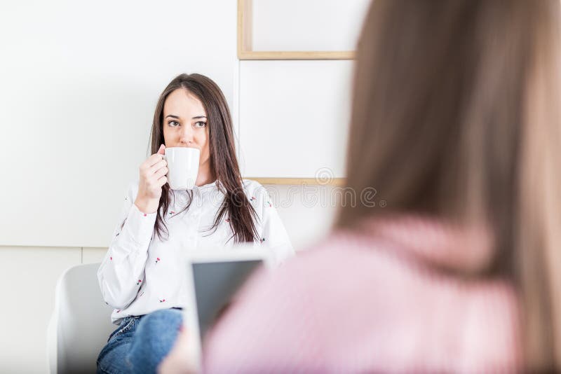 Twee jonge moderne wijfjes die koffie drinken en tabletapparaat in modern bureau met behulp van stock foto's Twee jonge moderne wijfjes die koffie drinken en tabletapparaat in modern bureau met behulp van stock foto's
