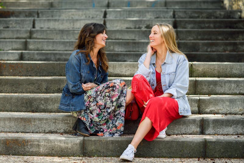 Twee jonge vrouwen die en op stedelijke stappen spreken lachen stock foto Twee jonge vrouwen die en op stedelijke stappen spreken lachen stock foto