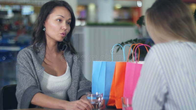 Twee jonge vrouwen discussiëren in café in het winkelcentrum