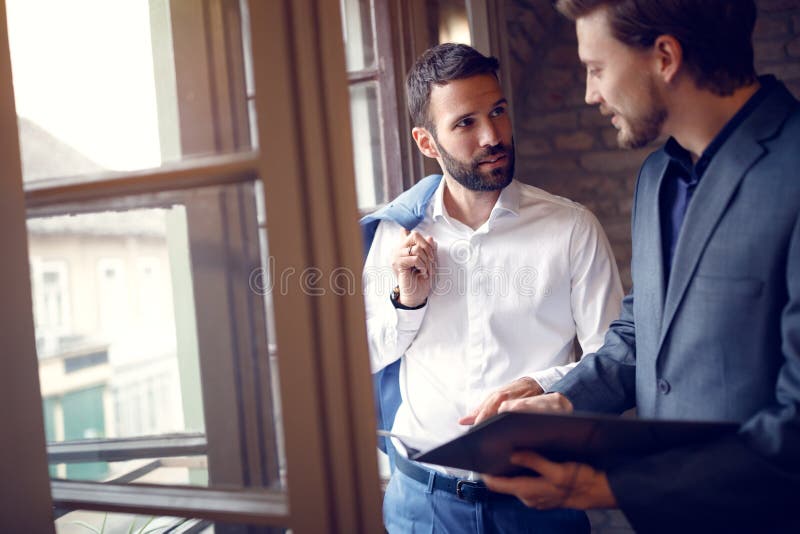 Twee jonge zakenlieden die in bureau spreken stock afbeeldingen Twee jonge zakenlieden die in bureau spreken stock afbeeldingen