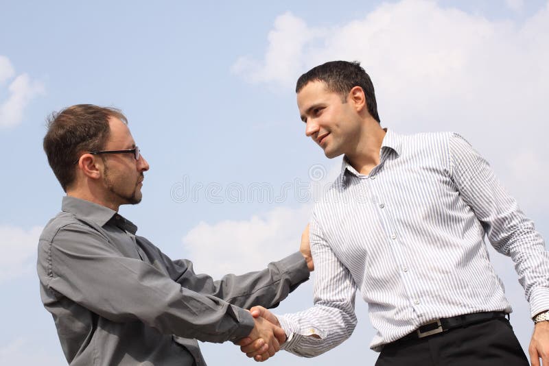 Twee jonge zakenlieden die handen schudden
