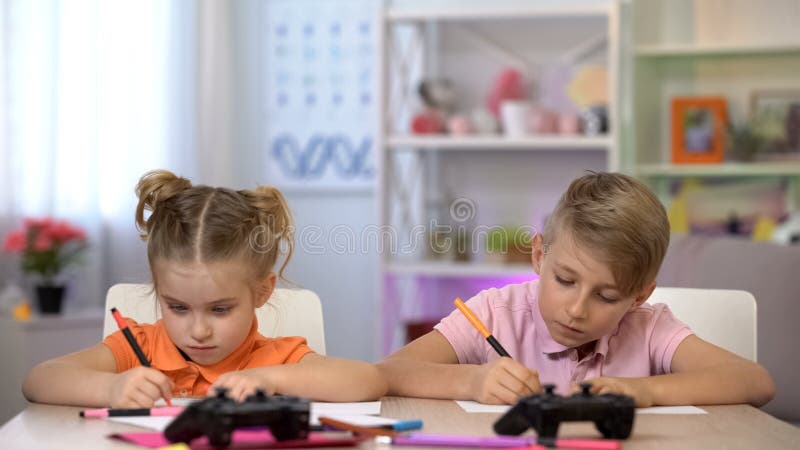 Twee kinderen die beelden die met viltpennen, consoles trekken op lijst liggen royalty-vrije stock fotografie Twee kinderen die beelden die met viltpennen, consoles trekken op lijst liggen royalty-vrije stock fotografie