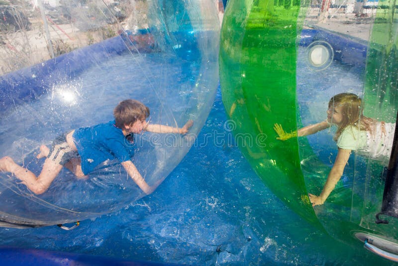Twee kinderen die pret in een opblaasbare plastic ballon op hebben stock afbeeldingen Twee kinderen die pret in een opblaasbare plastic ballon op hebben stock afbeeldingen