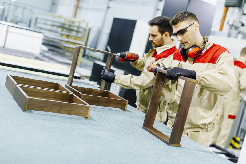 Twee knappe jonge mensen die in meubilairfabriek werken stock foto Twee knappe jonge mensen die in meubilairfabriek werken stock foto