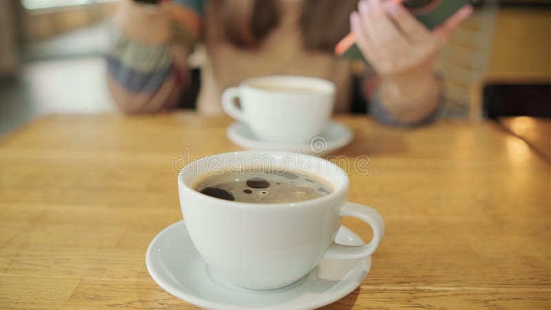 Twee kopjes koffie op een houten tafel die een lui koffiepauze in een comfortabele omgeving vertegenwoordigen.