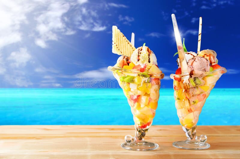 Twee koppen van fruitsalade met overzees op de achtergrond stock afbeeldingen Twee koppen van fruitsalade met overzees op de achtergrond stock afbeeldingen
