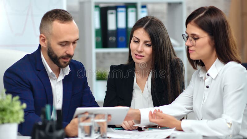 Twee lachende vrouwelijke werknemer die onderzoeksgegevens op de markt brengt aan mannelijke baas met behulp van tabletpc