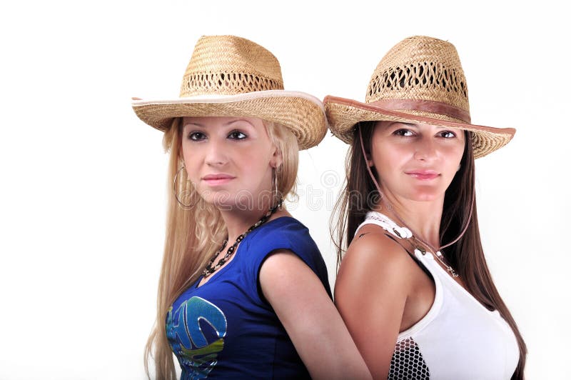 Twee Meisjes die de Hoeden en het Glimlachen van de cowboy dragen stock foto's Twee Meisjes die de Hoeden en het Glimlachen van de cowboy dragen stock foto's
